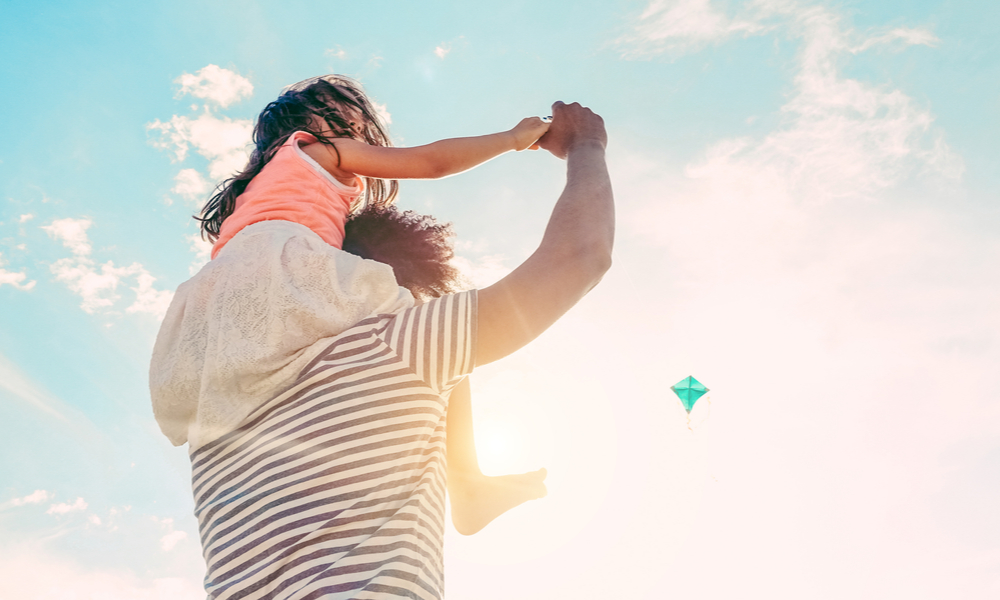 A father with his young daughter sitting on his shoulders.